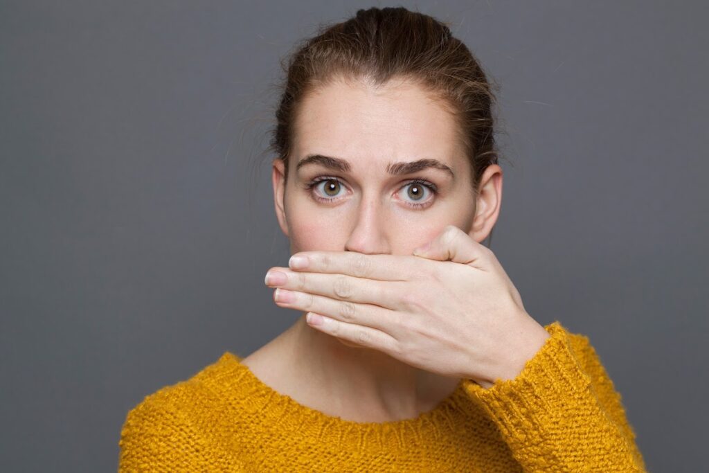 Woman holding her hand in front of her mouth